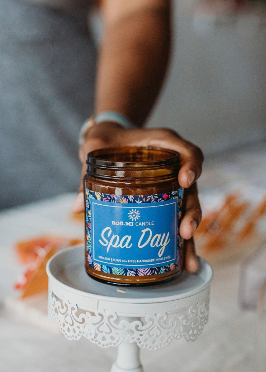 Person holding a jar labeled 'Spa Day' on a small white stand.